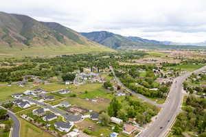 Aerial view of property and surrounding area featuring a mountainous background and nearby suburban area