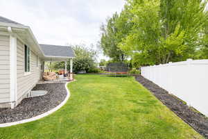 View of yard with a trampoline and a patio area