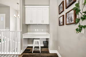 Unfurnished office with dark wood-style floors, baseboards, and a chandelier