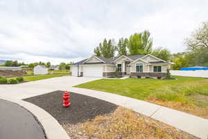 Craftsman inspired home featuring an attached garage, concrete driveway, stone siding, and a storage shed