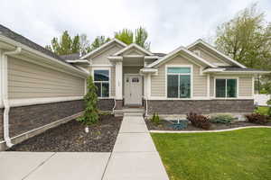 Craftsman-style home with stone siding, board and batten siding, and a front yard