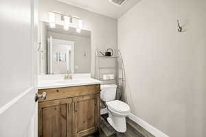 Bathroom featuring toilet, wood finished floors, vanity, and baseboards