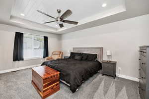 Bedroom with a raised ceiling, baseboards, carpet, recessed lighting, and ceiling fan