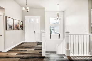 Foyer entrance with a chandelier, wood finished floors, and healthy amount of natural light