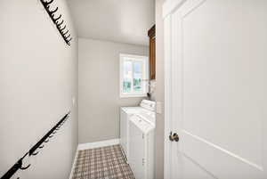 Washroom featuring washer and clothes dryer, cabinet space, baseboards, and tile patterned floors