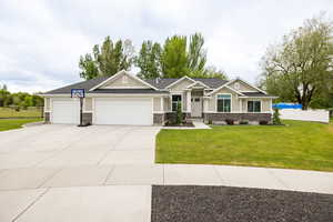 Craftsman-style home featuring an attached garage, driveway, board and batten siding, and stone siding