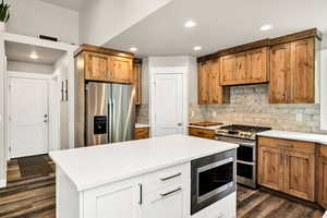 Kitchen featuring stainless steel appliances, dark wood finished floors, recessed lighting, tasteful backsplash, and light countertops