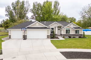 Craftsman-style house with stone siding, board and batten siding, a front yard, a garage, and concrete driveway