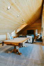 Rec room with wood ceiling, rustic walls, carpet flooring, lofted ceiling, and billiards table
