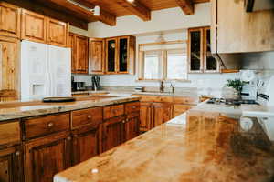 Kitchen with wooden ceiling, white appliances, glass insert cabinets, beam ceiling, and range hood