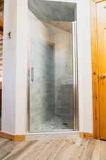 Full bathroom featuring a stall shower, wood finished floors, and baseboards