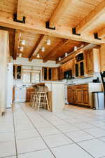 Kitchen with white appliances, wood ceiling, a breakfast bar area, beamed ceiling, and brown cabinets