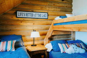Bedroom featuring log walls and wooden ceiling