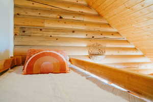 Unfurnished bedroom featuring log walls and wooden ceiling