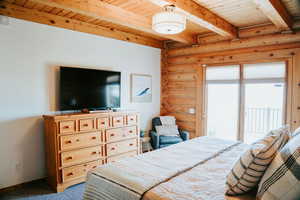 Bedroom featuring log walls, wood ceiling, beam ceiling, baseboards, and carpet floors