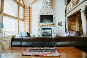 Living area featuring a fireplace, log walls, and high vaulted ceiling