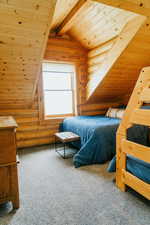 Carpeted bedroom with log walls and wooden ceiling