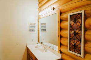 Bathroom featuring log walls and vanity