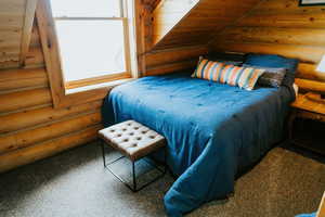 Bedroom featuring log walls and carpet floors