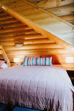 Bedroom featuring rustic walls, beamed ceiling, and wood ceiling