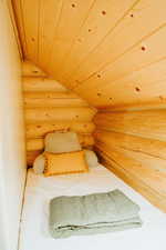 Bedroom featuring rustic walls and wooden ceiling