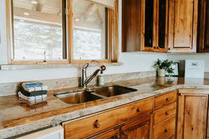 Kitchen featuring a sink, light stone counters, healthy amount of natural light, and brown cabinets