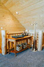 Carpeted home office with wood ceiling, rustic walls, and lofted ceiling