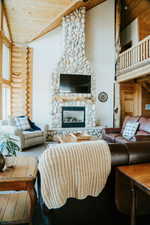 Living area featuring rustic walls, wooden ceiling, a stone fireplace, and vaulted ceiling