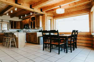 Dining space featuring wooden ceiling, light tile patterned floors, beam ceiling, and rustic walls