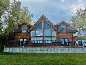 Back of property featuring french doors, a yard, and a wooden deck