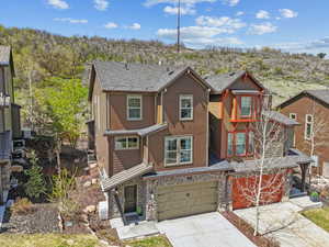 View of front of home featuring concrete driveway, a garage, stone siding, and stucco siding