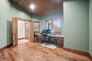 Office space with baseboards, lofted ceiling, light wood-type flooring, wood ceiling, and built in study area