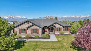 View of front of home with brick siding, a mountain view, and a front yard