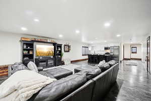 Living area featuring baseboards, concrete flooring, and recessed lighting