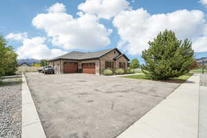View of front of house with an attached garage, asphalt driveway, brick siding, fence, and roof with shingles