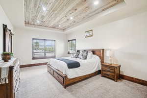 Carpeted bedroom featuring a tray ceiling, wood ceiling, recessed lighting, baseboards, and a barn door