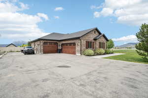 View of front of home featuring brick siding, a garage, a mountain view, driveway, and a shingled roof
