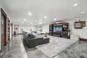 Living room featuring finished concrete flooring, recessed lighting, and baseboards