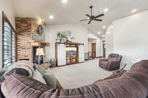 Living area featuring carpet, a brick fireplace, lofted ceiling, ceiling fan, and recessed lighting