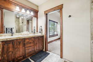 Bathroom featuring a shower stall, tile patterned flooring, double vanity, and baseboards