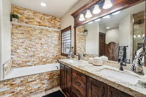 Full bathroom featuring tiled tub, tile patterned flooring, double vanity, and a tile shower