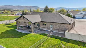 Rear view of house with roof with shingles, brick siding, a patio, entry steps, and a mountain view