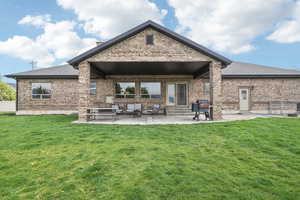 Rear view of property featuring entry steps, brick siding, a patio, and a shingled roof