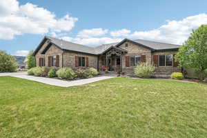 View of front of house featuring brick siding, a front lawn, and roof with shingles
