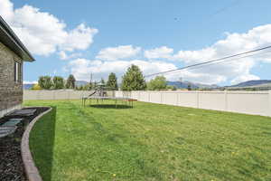 View of yard with a trampoline, a mountain view, and a playground