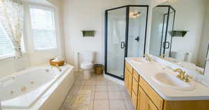 Bathroom with toilet, a whirlpool tub, a stall shower, double vanity, and tile patterned flooring