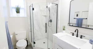 Full bath with a marble finish shower, toilet, and vanity