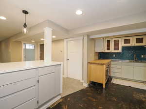Kitchen featuring recessed lighting, glass insert cabinets, backsplash, pendant lighting, and a sink