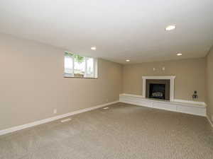 Basement featuring recessed lighting, a fireplace with raised hearth, carpet, and baseboards