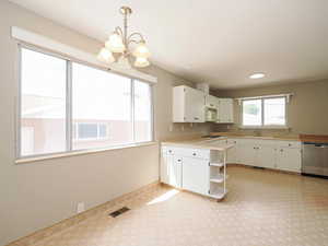 Kitchen with stainless steel dishwasher, white microwave, open shelves, a chandelier, and a sink